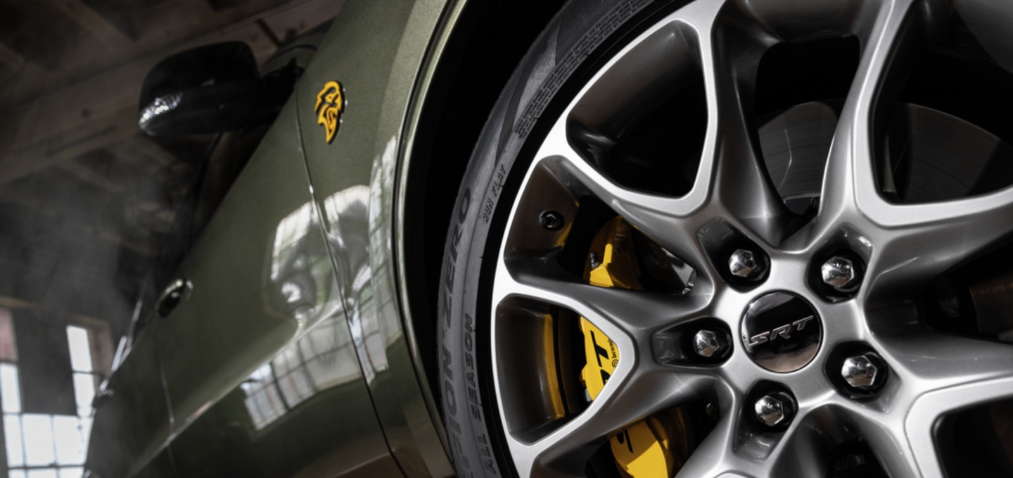 Un primer plano de la rueda y neumático delanteros del lado del pasajero de un Dodge Durango SRT Hellcat Jailbreak 2027. Toma desde un ángulo bajo.