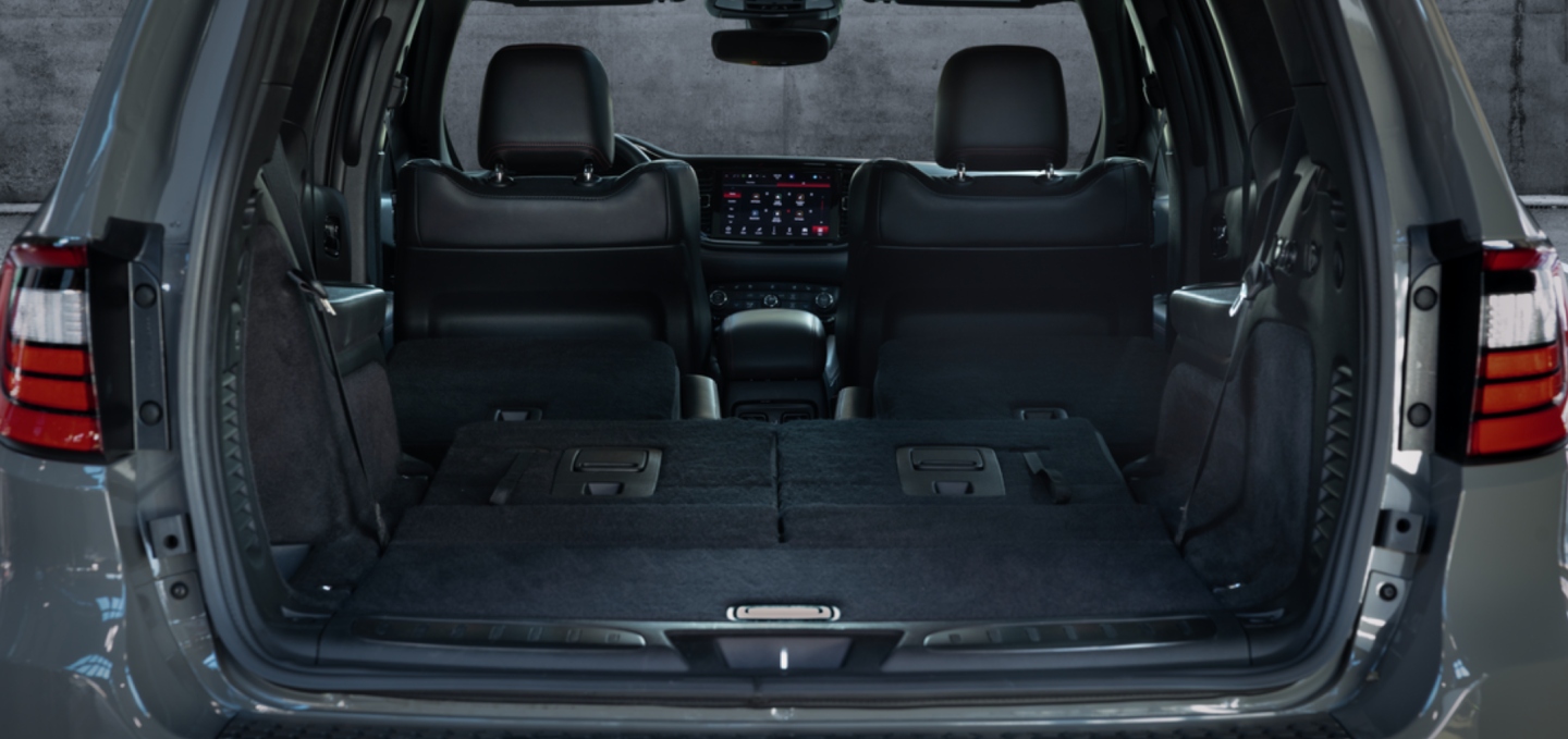 La zona de carga de un Dodge Durango GT Hemi V8 2027 con los asientos de la trcera fila plegados. Toma a través de la puerta trasera levadiza abierta.