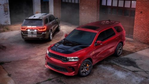 Dos modelos Dodge Durango 2027 estacionados en un callejón. A la izquierda, un Durango SRT Hellcat Jailbreak​​​ gris con dos franjas centrales blancas y a la derecha, un Durango SRT Hellcat Jailbreak rojo con inserción en el capó negra.
