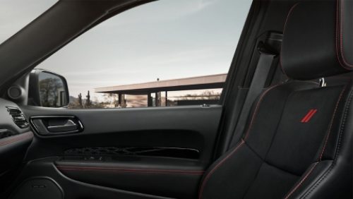 El asiento del pasajero delantero tapizado en cuero con costuras rojas en un Dodge Durango R/T 392 2027. Toma desde el lado del conductor.
